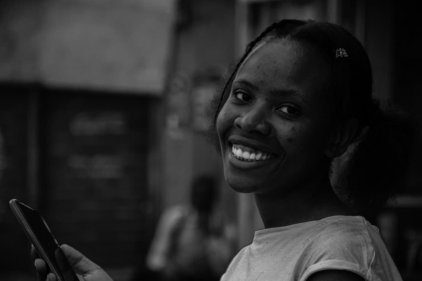 Woman smiling while holding her phone, in black and white